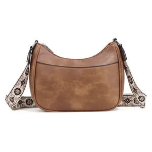 Close-up of brown crescent hobo bag with floral patterned wide strap and silver zipper detail