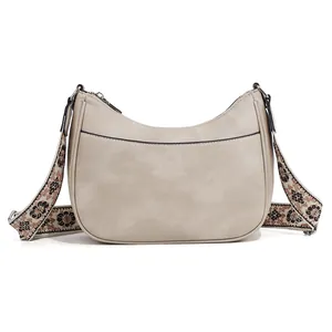Detail of cream crescent bag featuring ethnic patterned strap and smooth faux leather