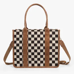 Detail of checkered tote bag featuring brown leather trim and detachable shoulder strap