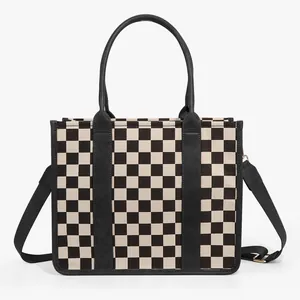 Close-up of black and white checkerboard tote bag with premium leather handles and straps