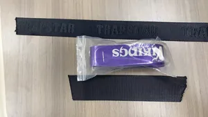 Dettaglio di braccialetti in tessuto nero e viola con stampa di marca alla moda
