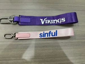 Dettaglio di portachiavi a polso in tessuto resistente con ganci in metallo viola e rosa