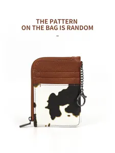 Detail of cow print card holder showing multiple slots and black metal zipper with chain
