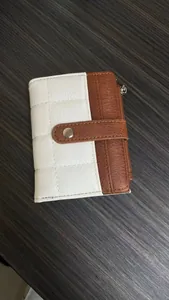 Detailed view of quilted faux leather wallet with snap closure on a dark wooden surface