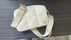 Detail of off-white quilted crossbody bag with jacquard strap and gold-tone hardware