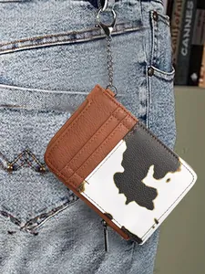 Detail of cow print card holder with chain hanging on light blue denim jeans pocket