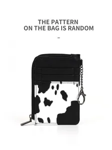 Detail of cow print card holder with three card slots, zipper pocket, and metal keychain