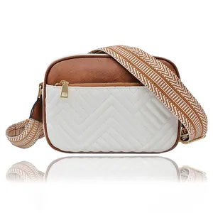 Detail of crossbody camera bag with brown faux leather, V-shaped quilting and woven strap