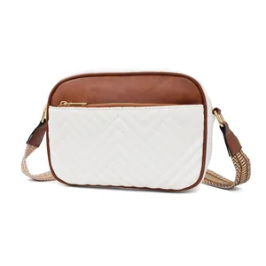 Detail of cow print crossbody bag with brown leather, quilted pattern and gold zipper
