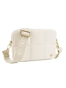 Detail of cream quilted crossbody bag featuring gold metal hooks and geometric woven strap