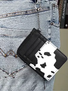 Detail of a cow print PU leather mini wallet with silver chain hanging on blue jeans