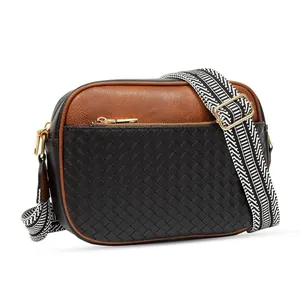Detail of crossbody camera bag with cow print patterns and wide woven shoulder strap