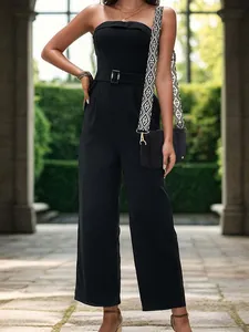 Close-up of black crossbody bag with geometric pattern wide strap on elegant jumpsuit