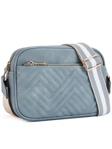 Detail of blue quilted camera bag with gold hardware and striped crossbody strap