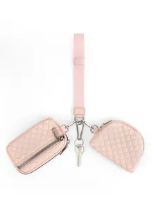 Detail view of pink quilted wristlet set with keychain and mini pouches on white background