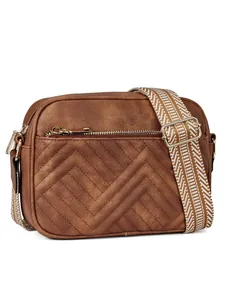Close-up of brown chevron quilted shoulder bag with patterned wide strap and gold zipper