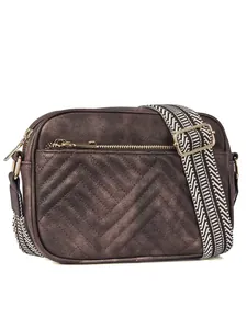 Macro shot of the chevron quilted texture and golden zipper on the crossbody camera bag
