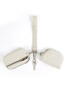 Detail of cream quilted wristlet set featuring small pouch, coin bag and metal key clip