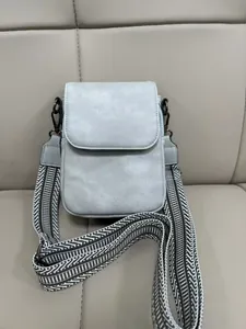 Dettaglio mini borsa grigio chiaro con ampia tracolla a righe bianche e nere