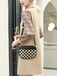 Detail of checkered crossbody bag with black leather and adjustable shoulder strap