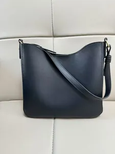 Detailed macro view of black pebbled leather texture and gold hardware on hobo bag