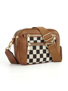 Détail du motif en damier sur le sac bandoulière en cuir PU marron avec zips dorés