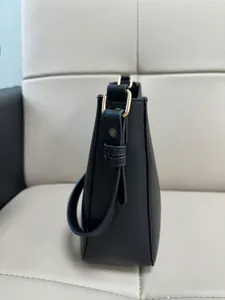 Detail of black leather bucket bag with litchi texture and gold hardware accents