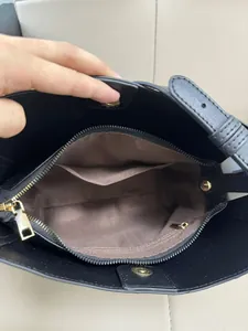 Interior view of black leather bucket bag showing brown lining and golden zip pocket