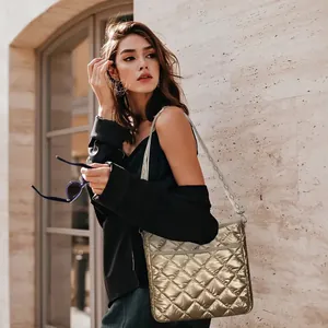 Detail of metallic gold quilted crossbody bag with adjustable wide logo print strap