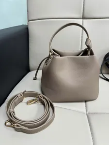 Detail of trendy lychee grain PU leather bucket bag with drawstring and gold hardware