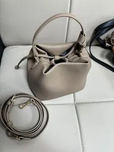 Detail view of beige drawstring bucket bag with pebble texture and gold hardware