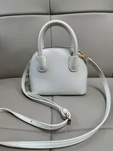 Détail du mini sac à main blanc texturé avec finitions dorées et double poignée