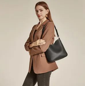 Minimalist black textured leather bucket bag styled with a brown blazer for office wear