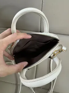Détail intérieur du sac en cuir grainé blanc avec doublure brune et finitions dorées