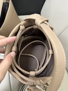 Top view of beige bucket bag interior with brown lining and adjustable shoulder strap