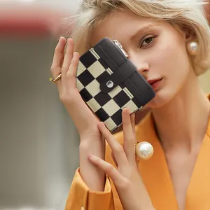Modisches Schachbrett-Kartenetui gehalten von Model im stylischen orangenen Blazer