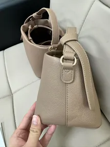 Detail of taupe pebbled leather bucket bag featuring top handle and adjustable strap