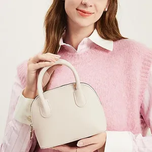 Détail d'un sac à main beige en similicuir avec fermeture éclair dorée et texture lisse