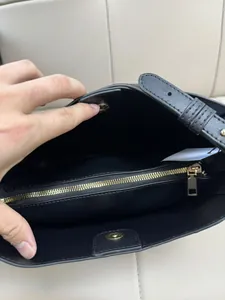 Interior view of black leather crossbody bag featuring a gold zipper pocket and magnetic closure