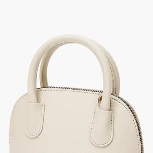 Gros plan du sac à main en cuir PU crème à texture litchi avec double poignée et zip doré