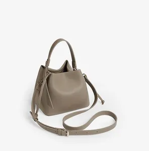 Detail of taupe pebbled leather bucket bag featuring a soft texture and adjustable strap