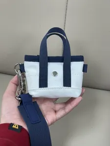 Dettaglio mini borsa in tela con cinturino blu scuro e moschettone in metallo argento