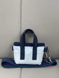 Dettaglio della mini borsa tote in tela con cinturini blu e moschettone argento