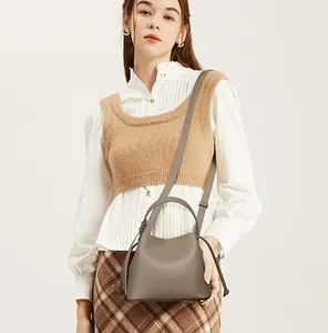 Minimalist taupe lychee leather handbag with drawstring detail on a model in a warm setting