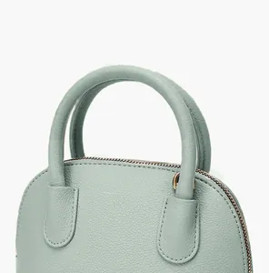 Détail des poignées rondes et coutures sur le sac à main en cuir grainé vert clair
