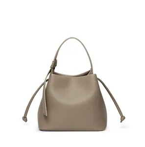 Detailed close-up of taupe bucket bag showing premium lychee grain leather and drawstring