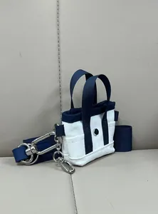 Dettaglio della mini borsa tote in tela blu e bianca con fibbia in metallo e tracolla