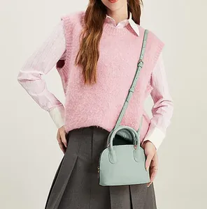 Petit sac bandoulière vert menthe porté avec un gilet rose et une jupe plissée