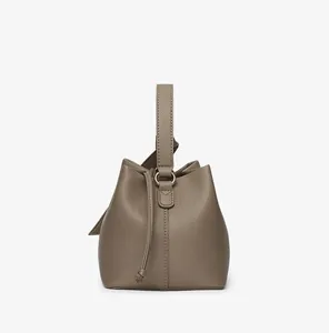 Close-up of taupe bucket bag showing premium lychee grain leather and drawstring detail