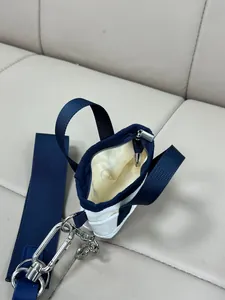 Dettaglio mini pochette in tela bianca con cerniera blu scuro e tracolla in nylon largo